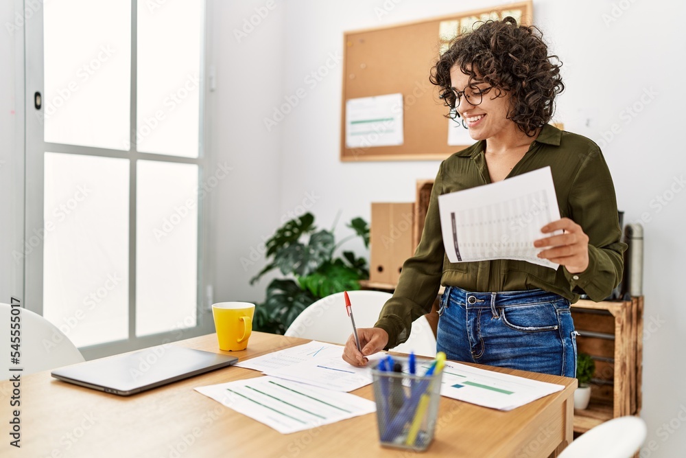 Young hispanic woman smiling confident writing on paperwork at office Young hispanic woman smiling confident writing on paperwork at office