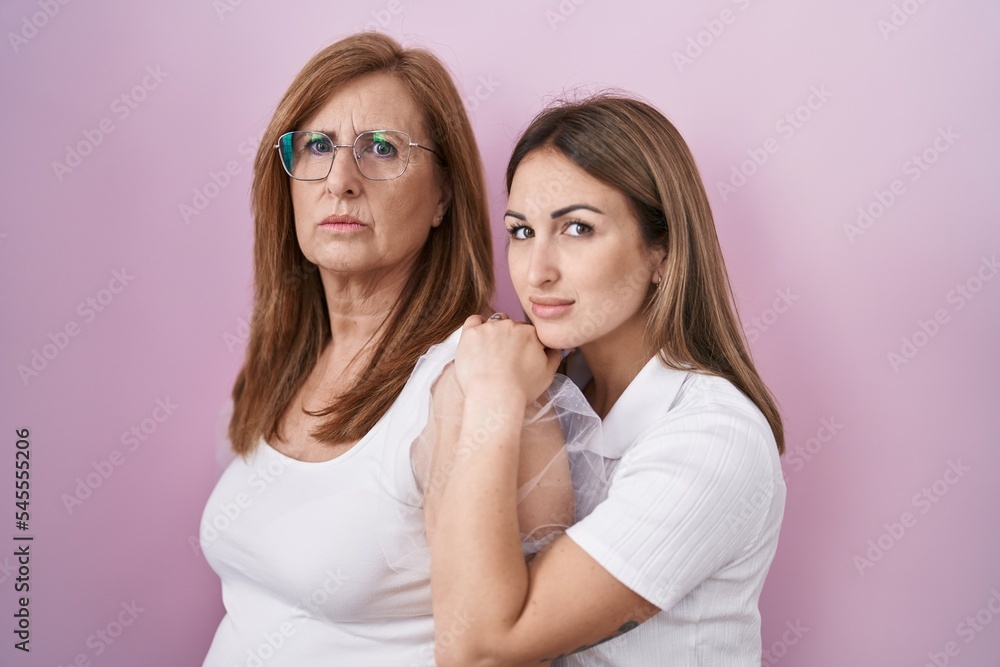 Hispanic mother and daughter wearing casual white t shirt relaxed with serious expression on face. simple and natural looking at the camera. Hispanic mother and daughter wearing casual white t shirt relaxed with serious expression on face. simple and natural looking at the camera.