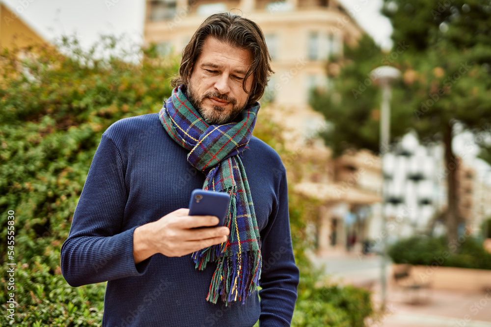Fototapeta premium Middle age handsome man using smartphone outdoors at the park