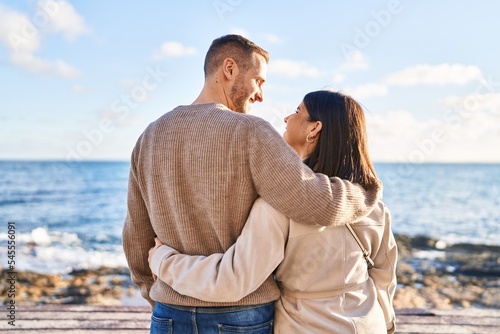 Man and woman couple hugging each other standing on back view at seaside