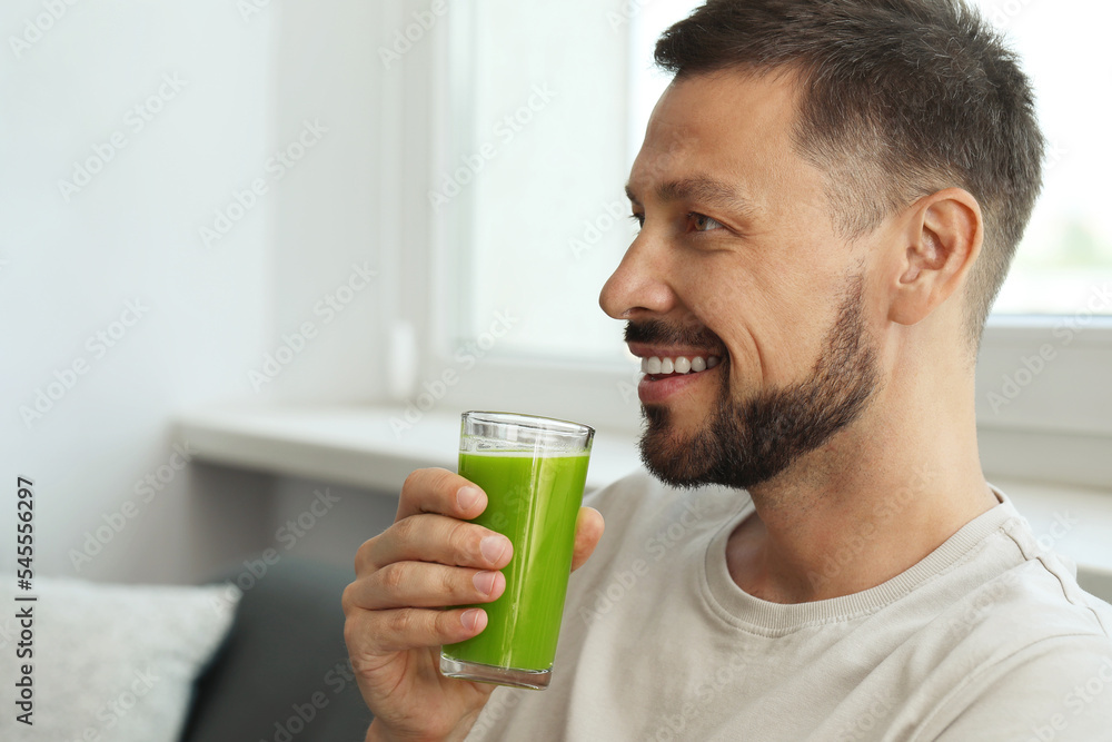 Man drinking delicious juice at home, space for text Man drinking delicious juice at home, space for text