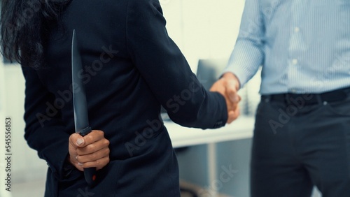 Fotografia Back view of businesswoman shaking hands with another businessman while holding a knife behind his back