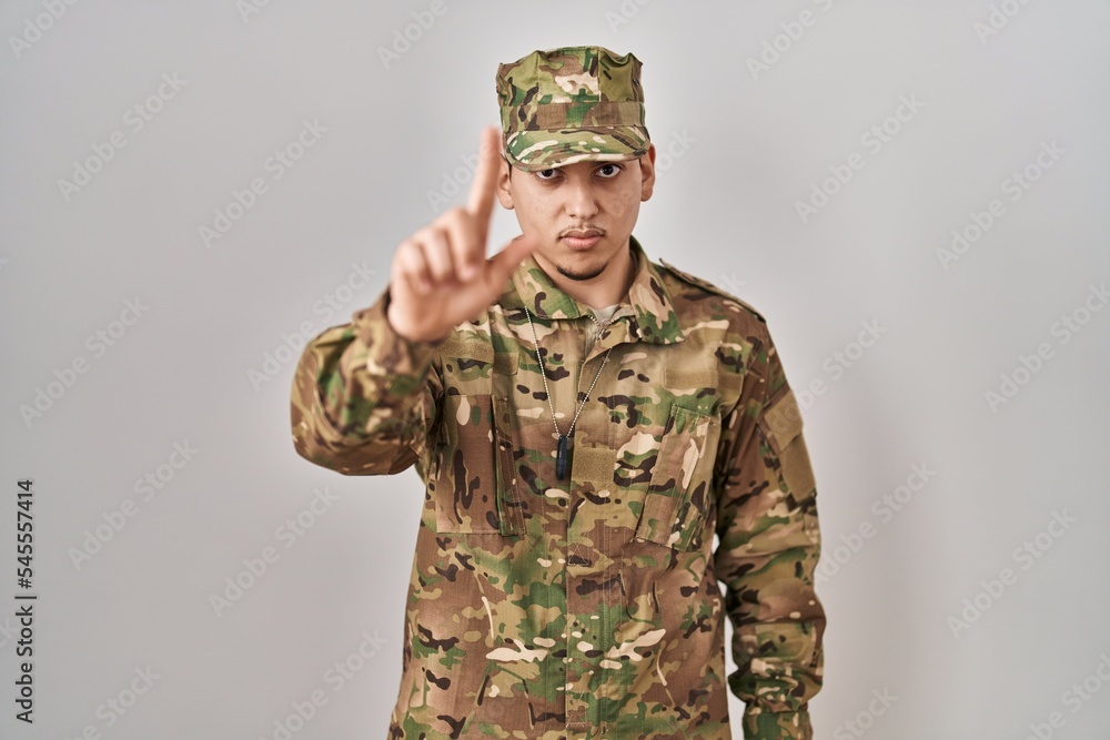 Young arab man wearing camouflage army uniform pointing with finger up and angry expression, showing no gesture Young arab man wearing camouflage army uniform pointing with finger up and angry expression, showing no gesture