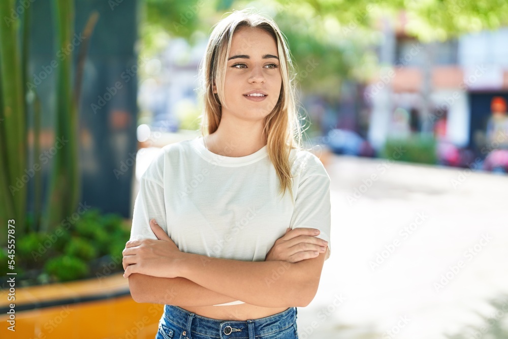 Young blonde woman standing with arms crossed gesture at park