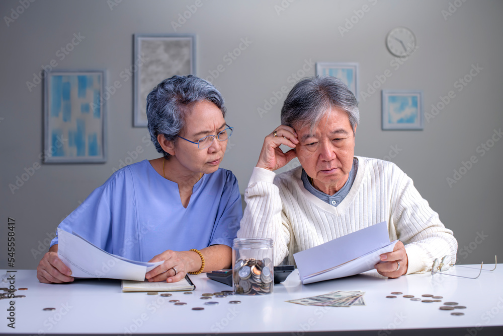 Worried Asian senior family couple reading financial documents or notification letter with bad news from bank while paying bills, retired husband and wife having money problems Worried Asian senior family couple reading financial documents or notification letter with bad news from bank while paying bills, retired husband and wife having money problems