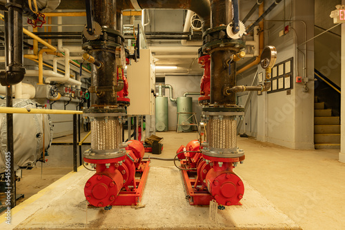 Принти на полотні The interior of an old and well used boiler room with two large mechanical pumps, pipes, valves and other equipment