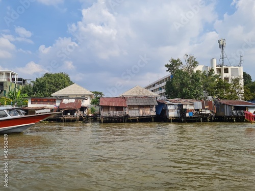 A village along the Chao Phraya River in Bangkok, with a boat.