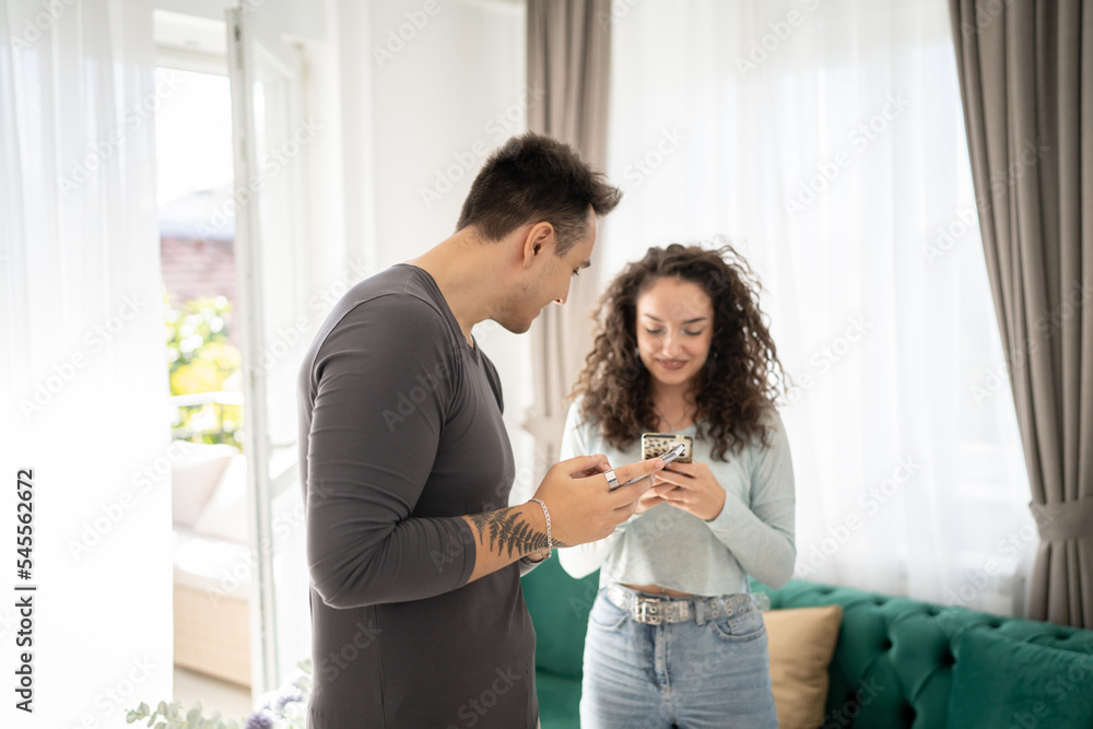 couple man woman use mobile phone smartphone at home texting online couple man woman use mobile phone smartphone at home texting online