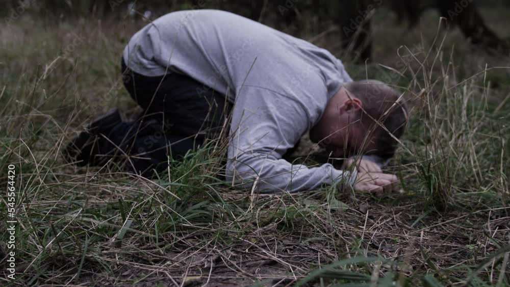 Young man lays on the ground crying and praying Young man lays on the ground crying and praying