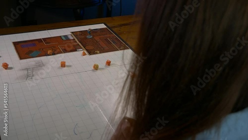 Woman Rolls Handful of Dice on a Game Mat With RPG Accessories photo