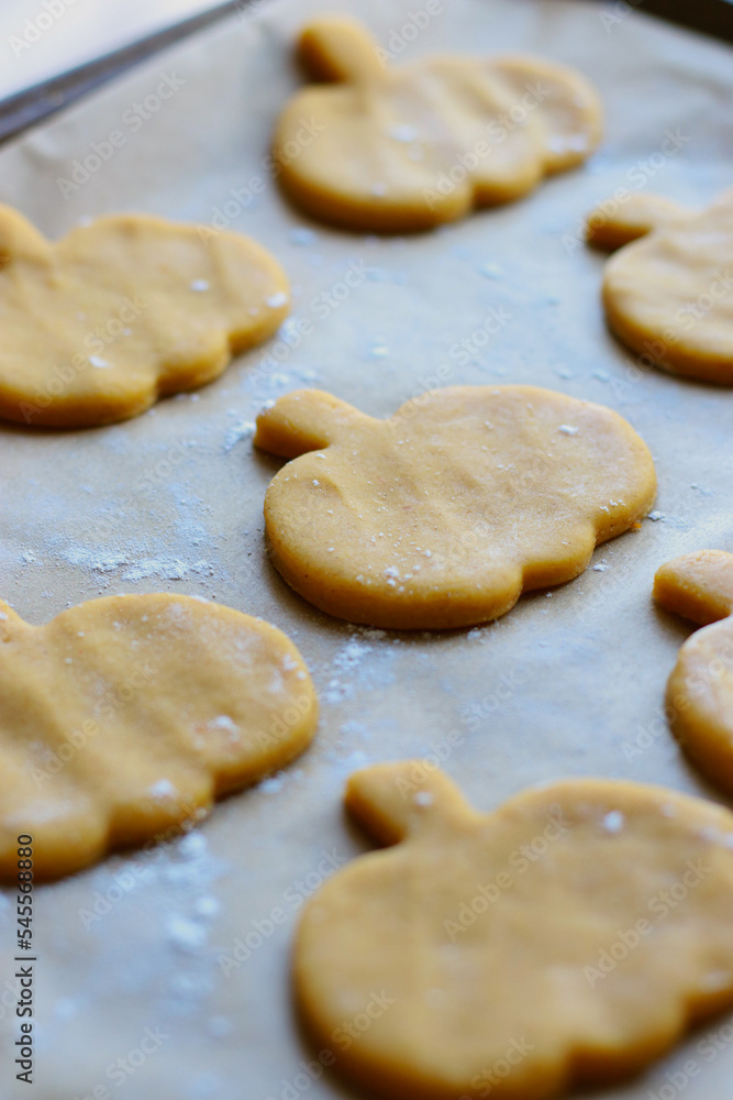 cut out cookies shapes of raw pumpkin dough on baking sheet
