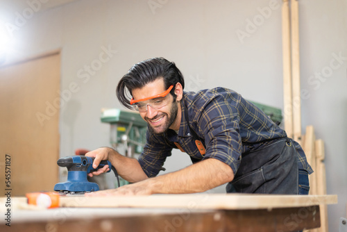 Carpenter man professional skill using electric sander for wood in carpentry shop