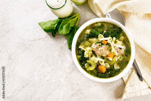 Soup with meatballs and pasta in bowl on granite top