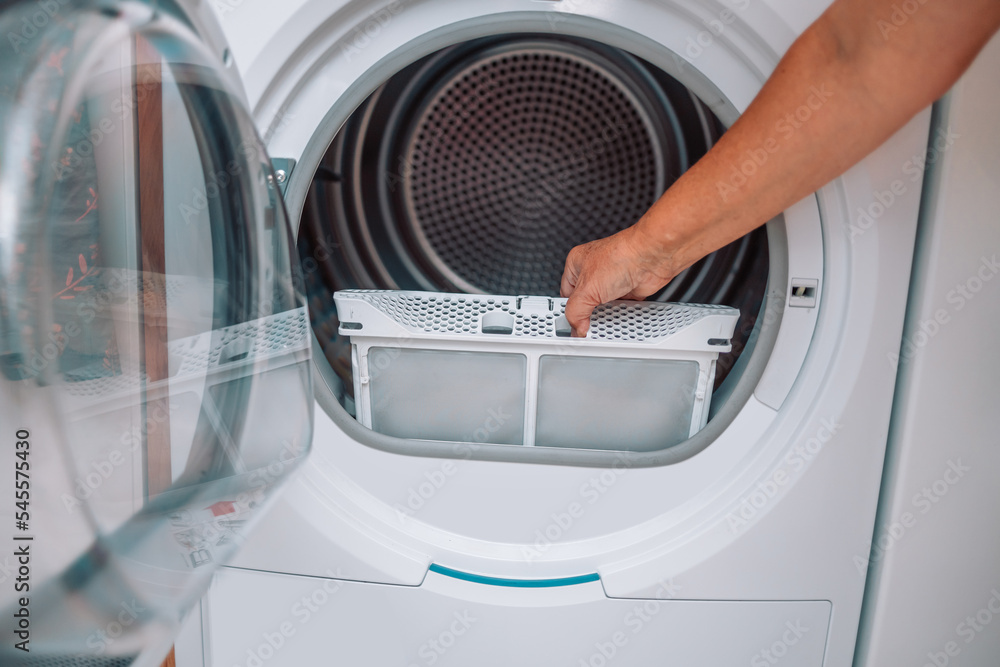 A housewife woman cleans the lint filter of the washing machine or tumble  dryer Stock Photo - Alamy