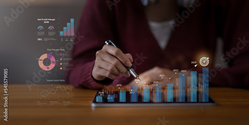 Businessman analyzes performance profitability of working companies with digital augmented reality graphics, positive indicators in 2023,2024 business calculates financial data for longterm investment photo