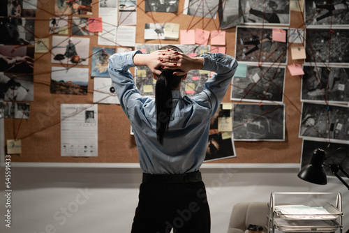 Fotografie Detective looking at evidence board in her office, back view