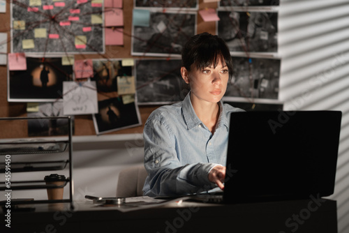 Detective processing evidence in her office using a laptop. photo