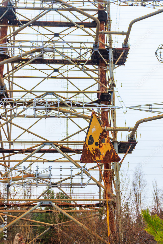 Fototapeta premium Radiation warning sign in front of Duga, a Soviet over-the-horizon (OTH) radar system as part of the Soviet anti-ballistic missile early-warning network, inside the Chernobyl Exclusion Zone in Ukraine