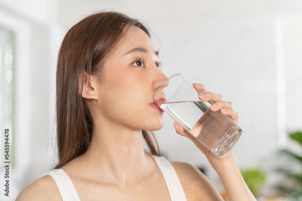 Happy beautiful, asian young woman, girl drinking, sip fresh glass of water for hydrate, holding transparent glass in her hand, thirsty at home. Health care, healthy lifestyle concept. Happy beautiful, asian young woman, girl drinking, sip fresh glass of water for hydrate, holding transparent glass in her hand, thirsty at home. Health care, healthy lifestyle concept.