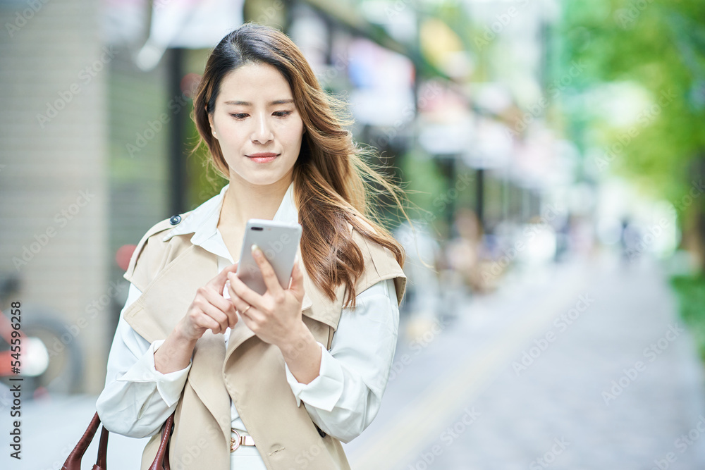 屋外でスマートフォンを手にする女性 屋外でスマートフォンを手にする女性