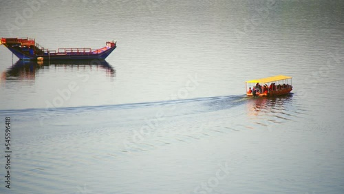 small boat taking tourists around a large ship marooned adrift in the middle of lake pichola near taj palace showing a popular tourist spot in the city of lakes udaipur photo