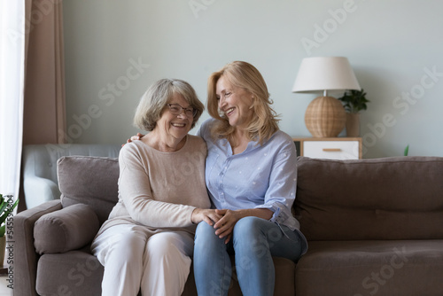 Tableau sur toile Middle-aged woman visit old mother, multi-generational family sit on sofa smile enjoy warm conversation and priceless time together