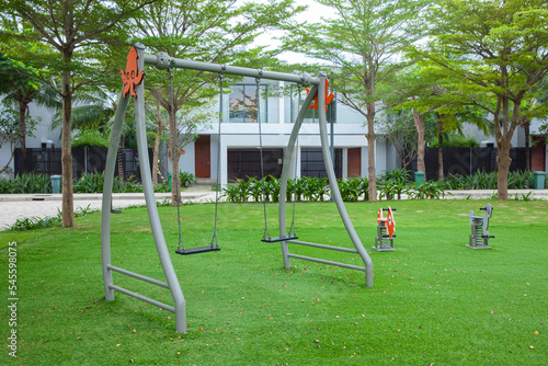 children colorful playground with plastic swing on green grass in the park