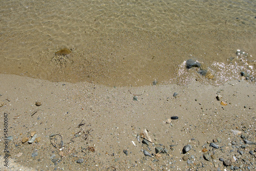 Sandy seashore with clear, transparent water with sun glare