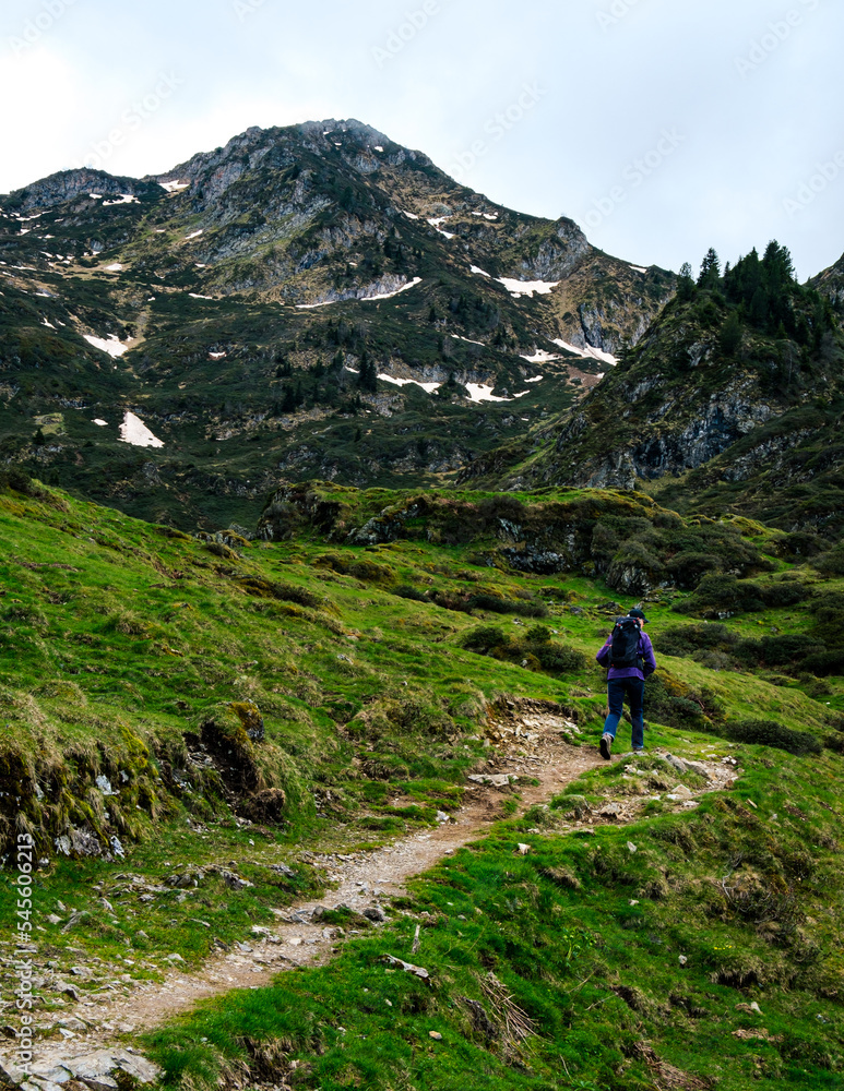 Man hiking near the Ayes lake in the French Pyrenees mountain range with snowi peaks on a cloudy and moody day