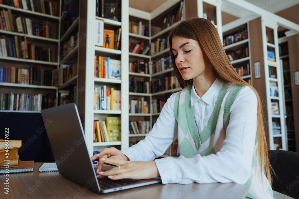 Female using laptop browsing internet in library Female using laptop browsing internet in library