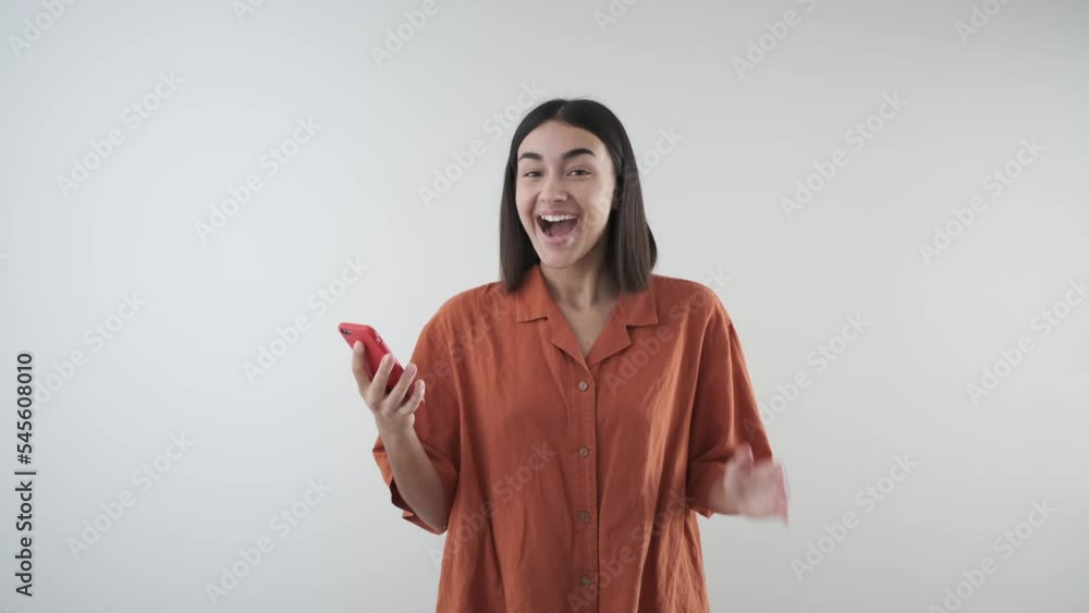 Happy young girl with mobile phone receives good news. Wide smile and cheerful Happy young girl with mobile phone receives good news. Wide smile and cheerful