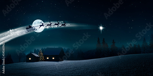 Santa Claus im Schlitten über einer Schneelandschaft bei Nacht