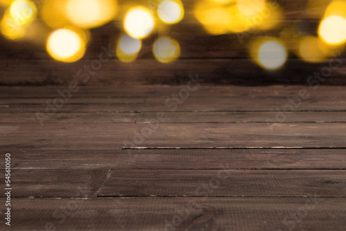 Brown wooden table with christmas lights in blur. Empty space for products for shop and store