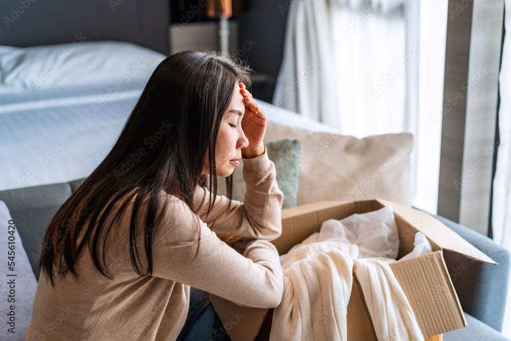 Dissatisfied young woman unpacking parcel at home received damaged and wrong online shopping order Dissatisfied young woman unpacking parcel at home received damaged and wrong online shopping order