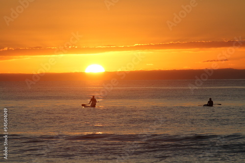 Kayakers and paddle boarder enjoy the sunsets on a New Zealand beach © Brian