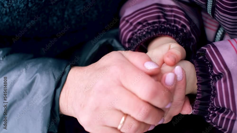Grandmother taking care of her little granddaughter warms her hands with her palms. An older Senior woman takes care of her family. Grandmother taking care of her little granddaughter warms her hands with her palms. An older Senior woman takes care of her family.