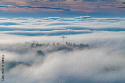 strommasten ragen aus dem nebel auf einem h  gel