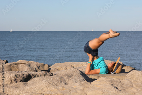 young slender girl with blue t-shirt and straw hat does gymnastic exercises
