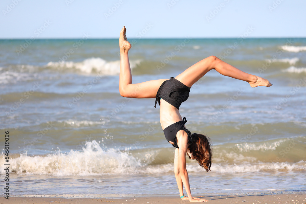 barefoot girl in black swimsuit from rhythmic gymnastics exercises on the seashore barefoot girl in black swimsuit from rhythmic gymnastics exercises on the seashore