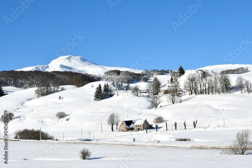 panorama sur le massif du sancy recouvert d'une épaisse couche de neige par une journée ensoleillée avec au loin un buron auvergnat proche de la station de ski de Super Besse dans le puy de dôme photo