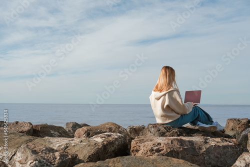 Remote work.Girl freelancer works remotely on the sea shore. workation, remote work,WFVH,Van Life vibes work from vacation home,work travel,remotely work.Travelling.Work from vacation remotely © shintartanya