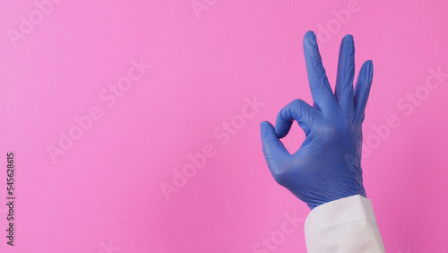 The A-Ok Hand Sign and doctor wear violet latex glove on pink background.