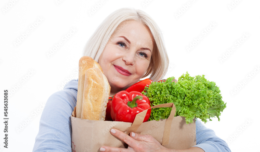 Happy woman with blond hair holds products from the store in paper bag of vegetables, bread and herbs red pepper and green lettuce in her hands for a healthy diet with vitaminswith. Happy woman with blond hair holds products from the store in paper bag of vegetables, bread and herbs red pepper and green lettuce in her hands for a healthy diet with vitaminswith.
