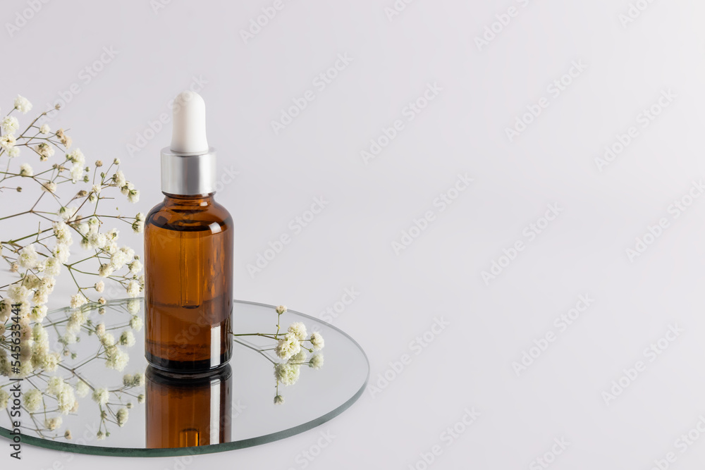 a cosmetic bottle with an amber glass dropper with an eco-natural remedy stands on a round mirror. an empty layout of a cosmetic brand. a copy space.
