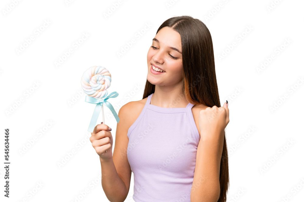 Teenager caucasian girl holding a lollipop over isolated background celebrating a victory Teenager caucasian girl holding a lollipop over isolated background celebrating a victory