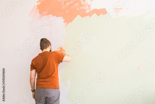 Young man using spatula and plastering of wall with white fresh finishing putty. Closeup. Repair work of home. Empty place for text. Side view.