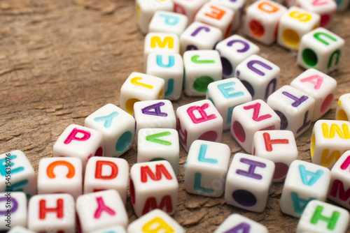 Set of dice with colorful letters on wooden table, shallow depth of field