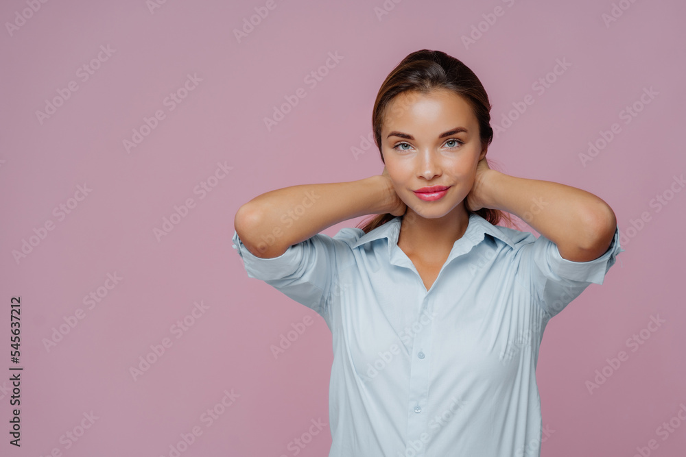 Indoor shot of brunette woman presses hair, has makeup, well cared complexion and fresh healthy skin, dressed in shirt, going to have walk with boyfriend, isolated over purple wall, copy space aside Indoor shot of brunette woman presses hair, has makeup, well cared complexion and fresh healthy skin, dressed in shirt, going to have walk with boyfriend, isolated over purple wall, copy space aside