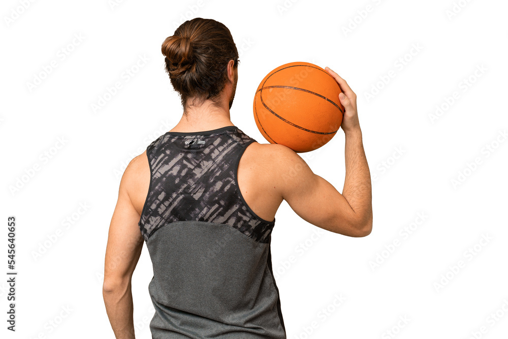 Young handsome man isolated on green chroma background playing basketball in back position