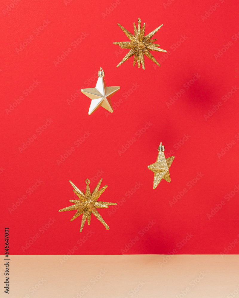Golden star shaped ornament levitate on red and beige background. Aesthetic vibrant New Year concept. Minima Christmas holiday idea. 